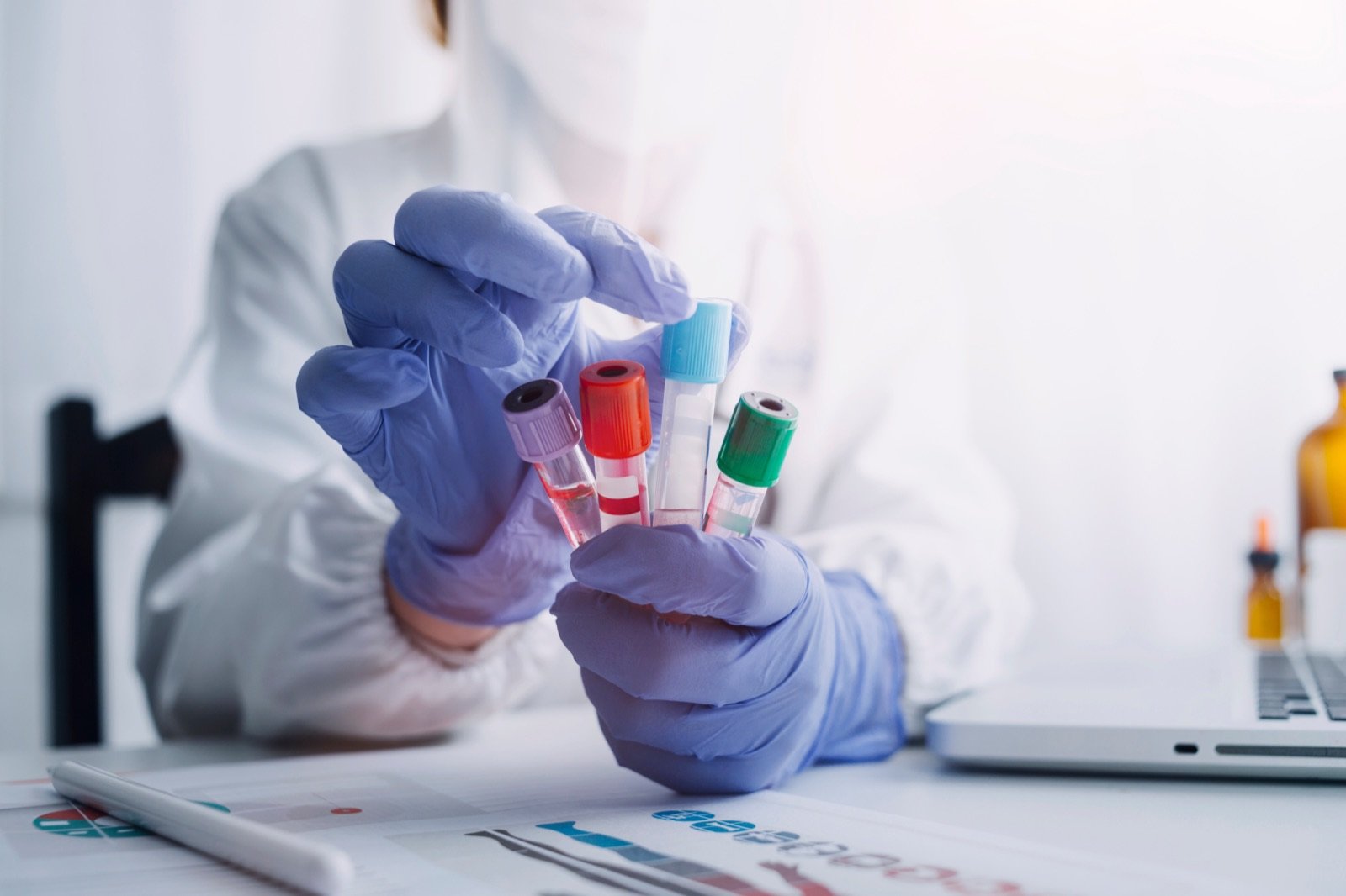 Gloved laboratory technician holding STAT blood specimen tubes